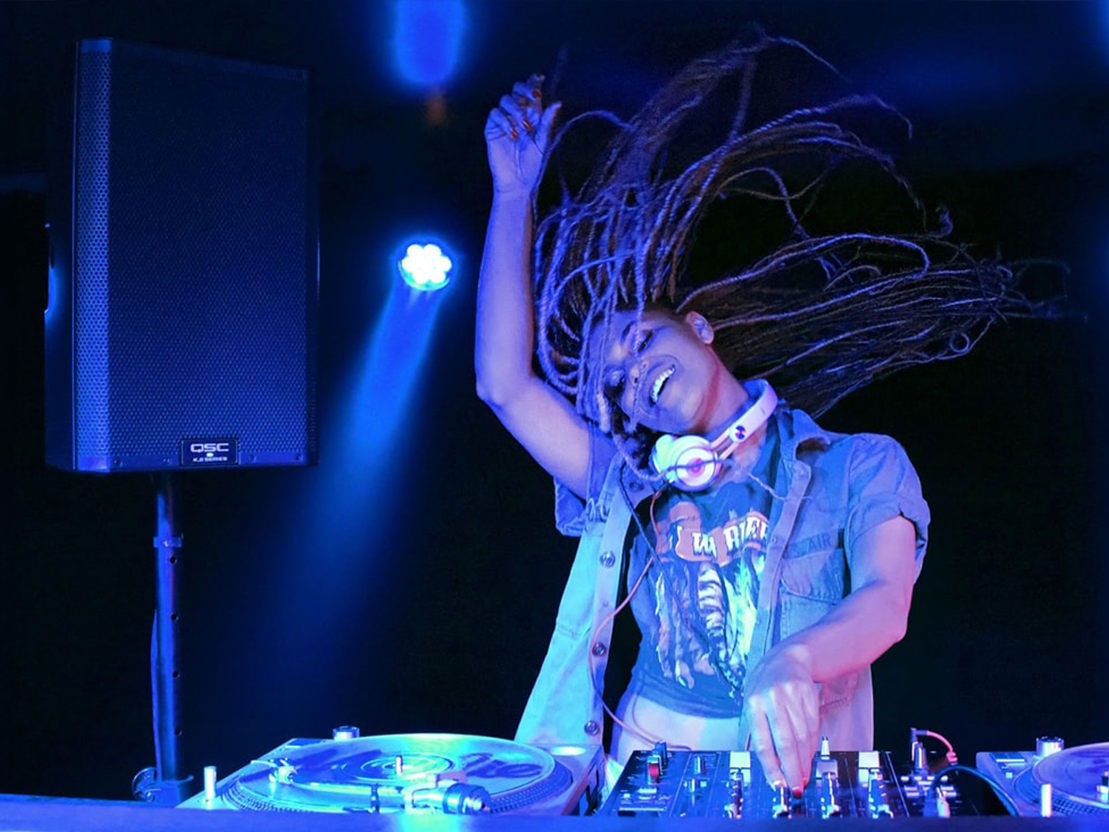 Kvinnlig DJ med mixerbord och högtalare